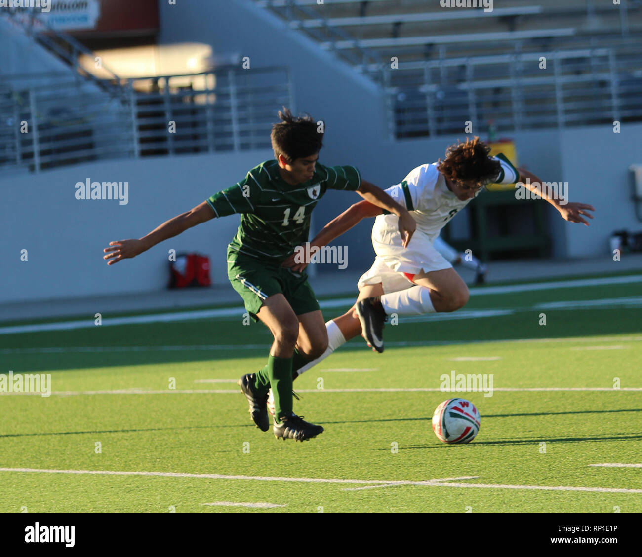 Soccer player goes flying past the ball after a shove from a defender during a boys high school game at Woodforest Bank Stadium in Shenandoah, Tex. Stock Photo