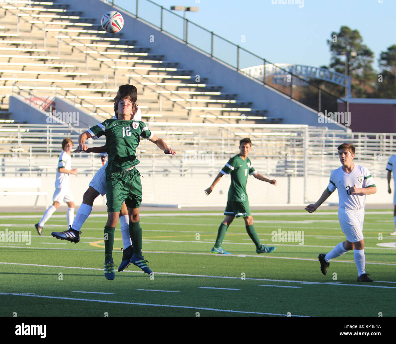 Two players leap into the air to head a soccer ball during a boys high