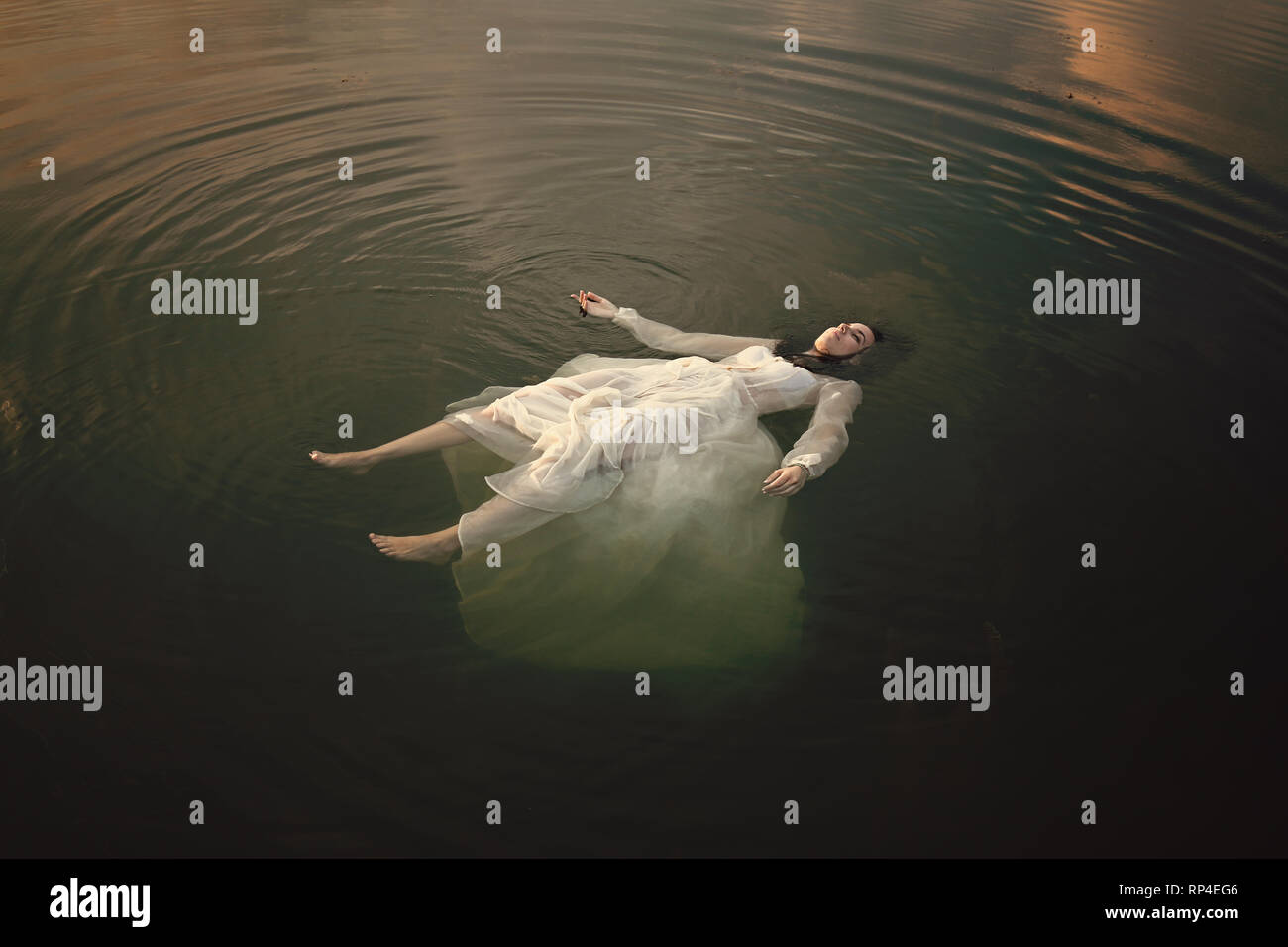 Young woman lying dead in lake waters Stock Photo