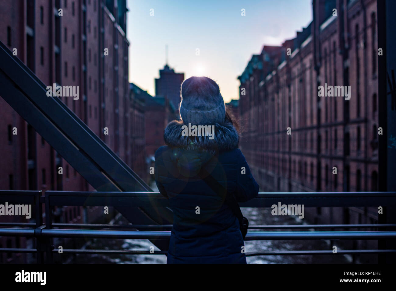 Back girl view. Girl standing on the bridge watching the modern building the sunset and soft light. Hamburg, hafencity with river and warehouses Stock Photo