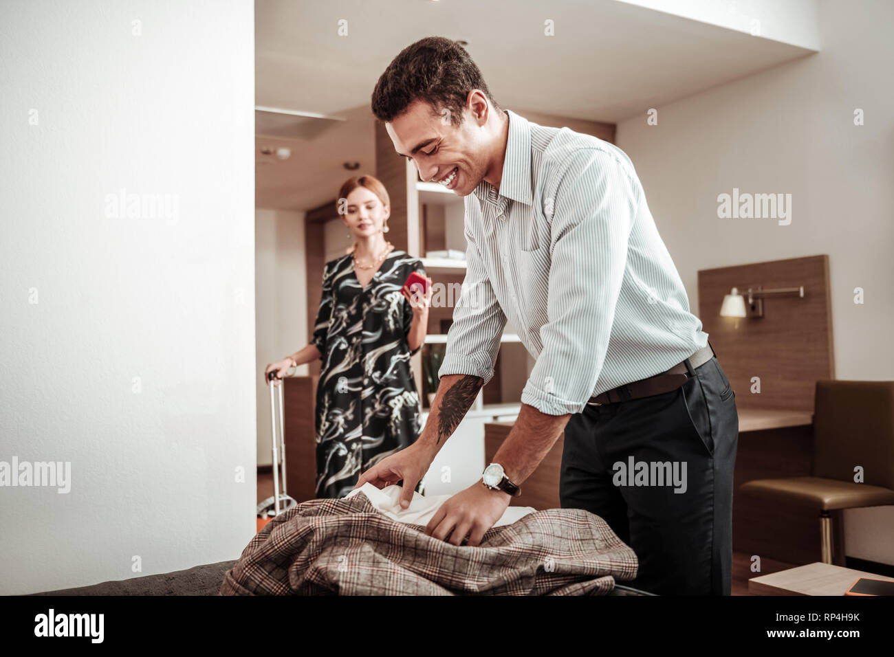 Boyfriend unpacking his suitcase having vacation with beloved Stock Photo