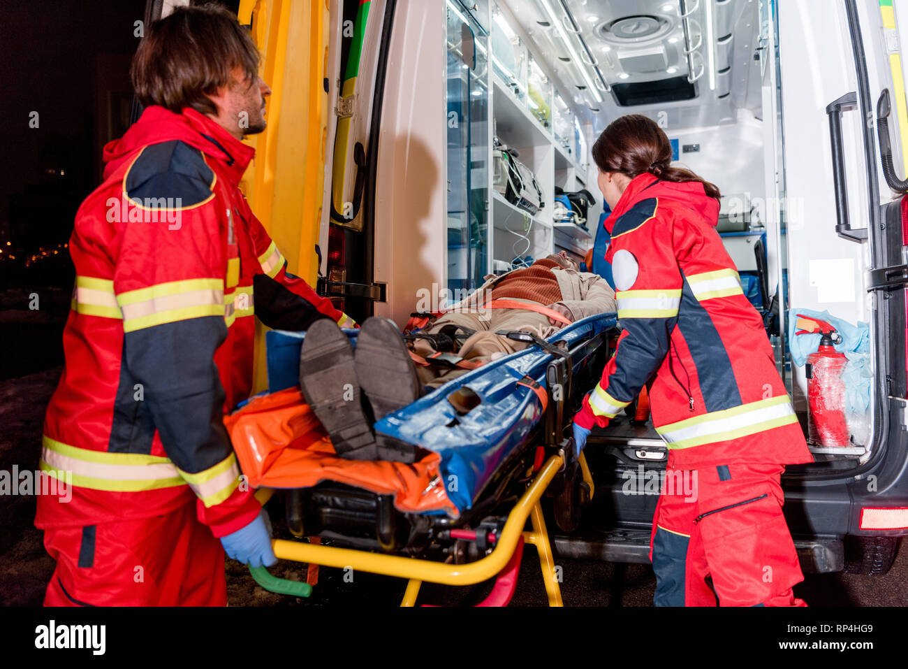 Paramedics transportating patient on gurney in ambulance car Stock