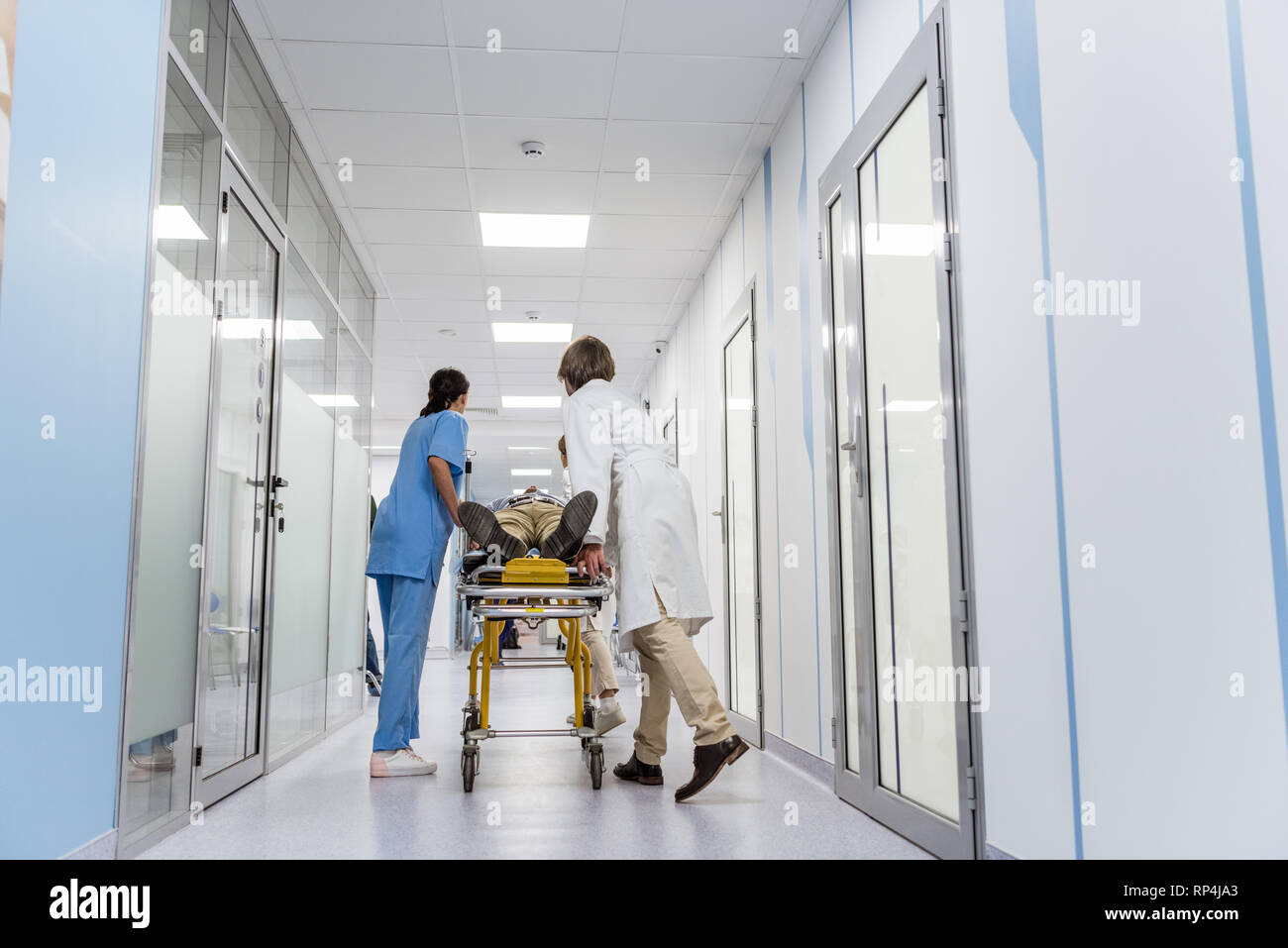 Doctors and nurse transporting unconscious patient on gurney Stock