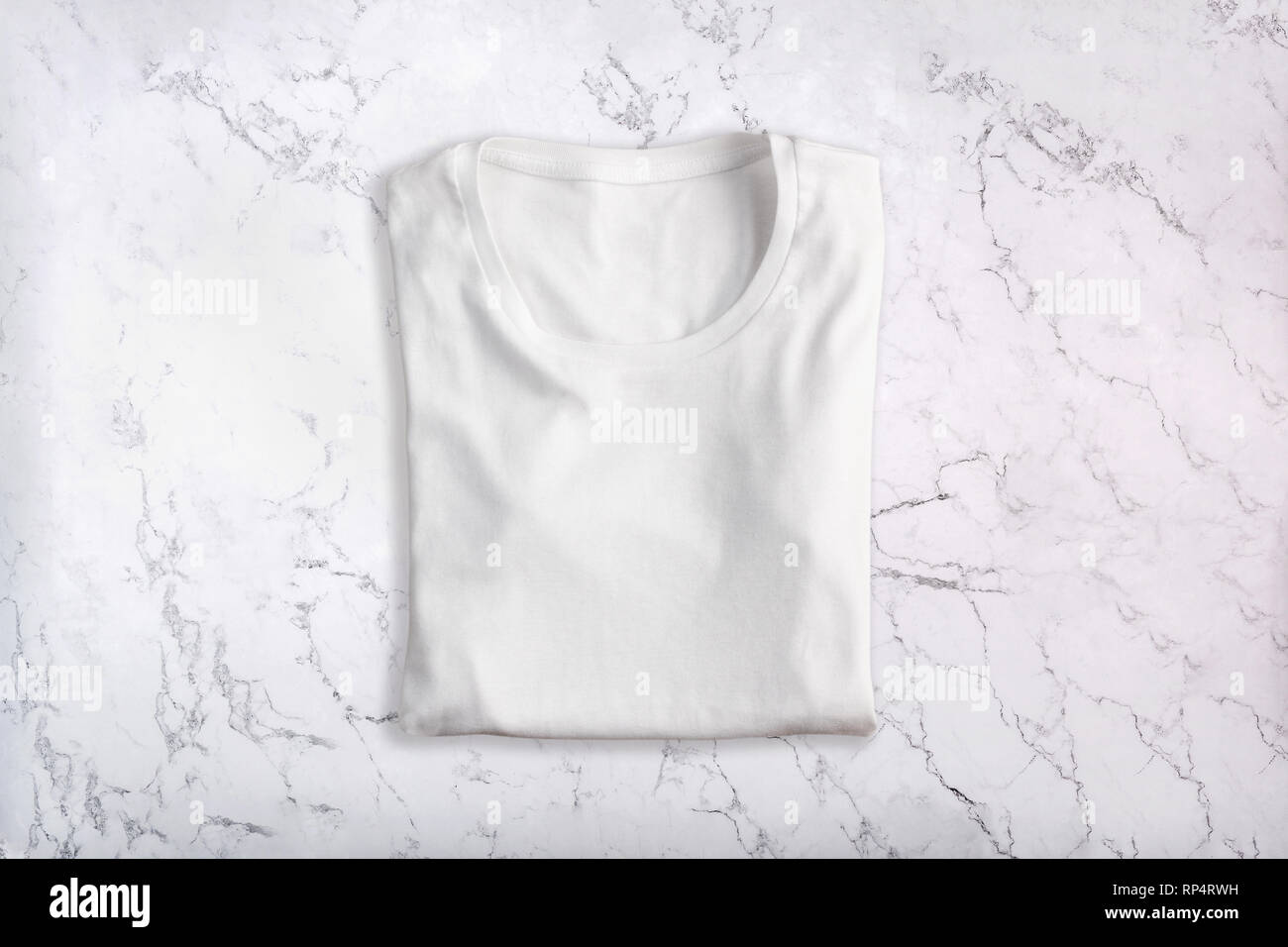 White folded t-shirt on marble background. Flat lay. Top view Stock Photo