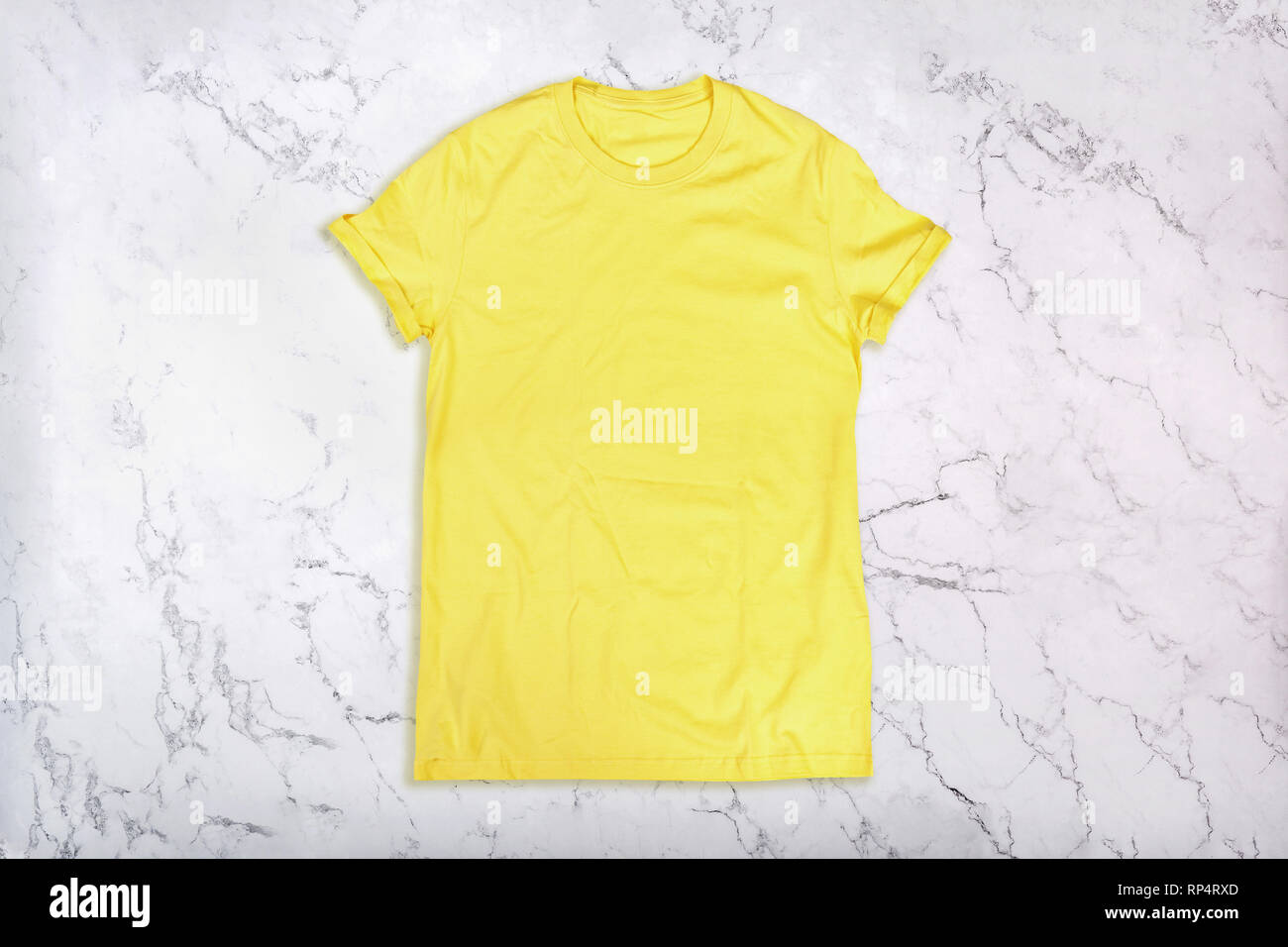 Yellow t-shirt on white marble background. Flat lay Stock Photo