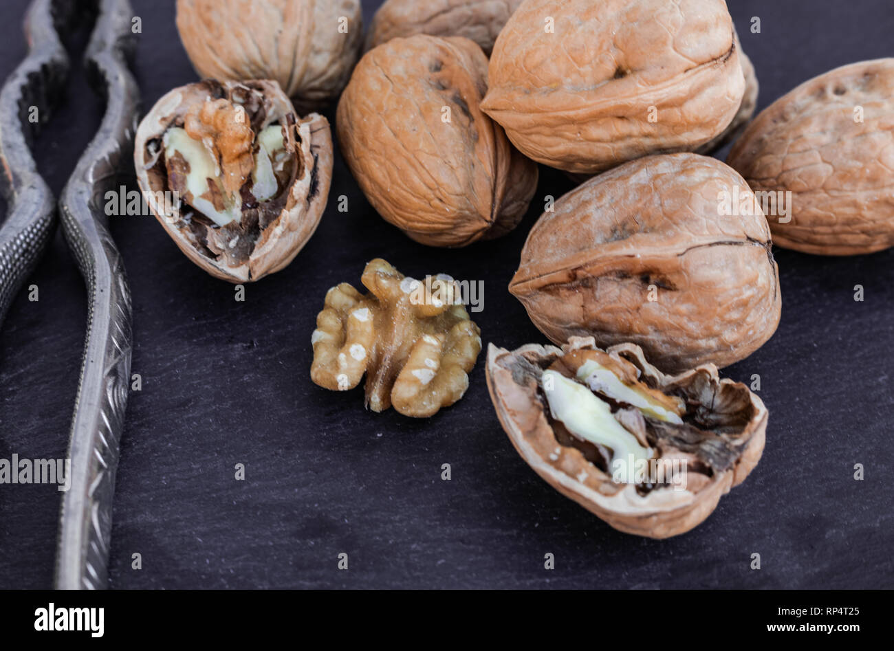 Walnuts and nutcracker on black surface Stock Photo