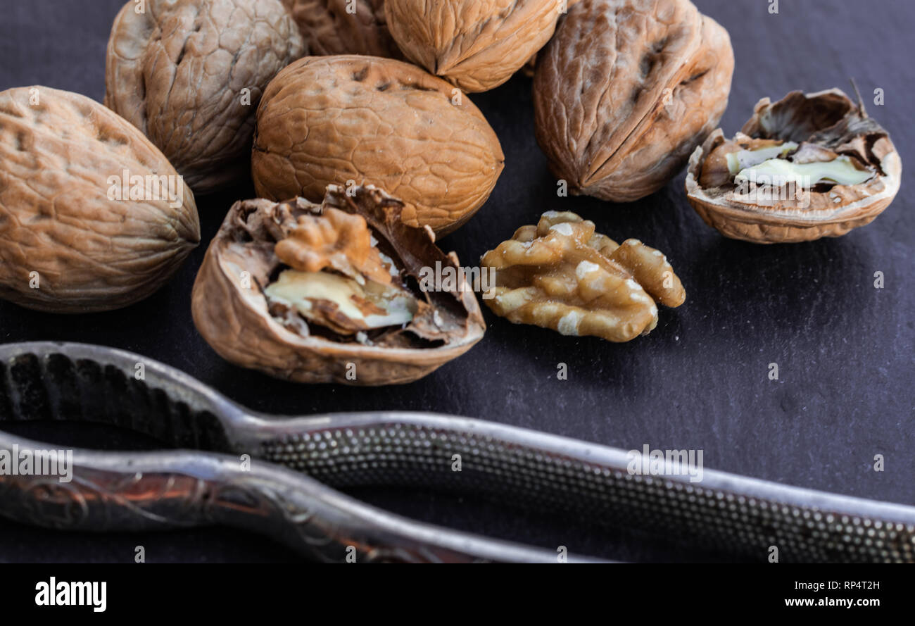 Walnuts and nutcracker on black surface Stock Photo