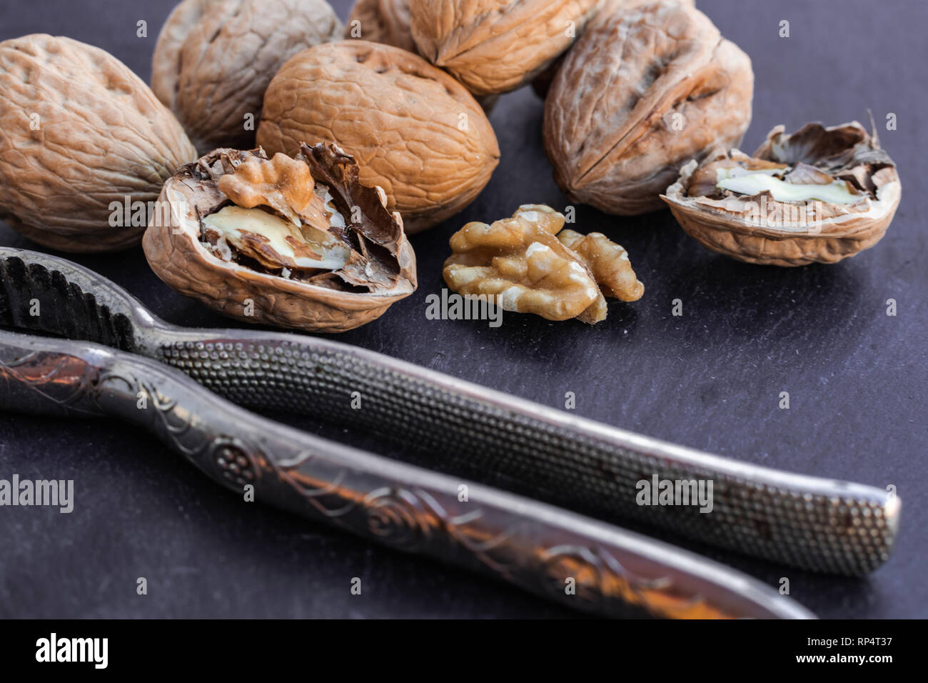 Walnuts and nutcracker on black surface Stock Photo