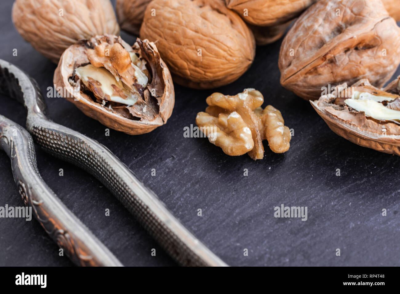 Walnuts and nutcracker on black surface Stock Photo