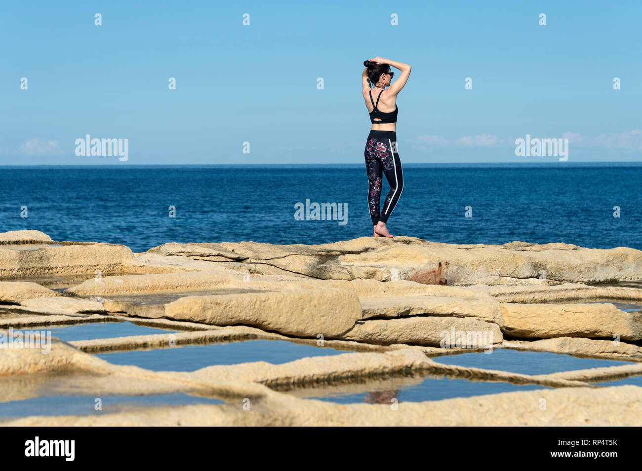 woman standing by the sea wearing sportswear, tying her hair up preparing to exercise Stock Photo