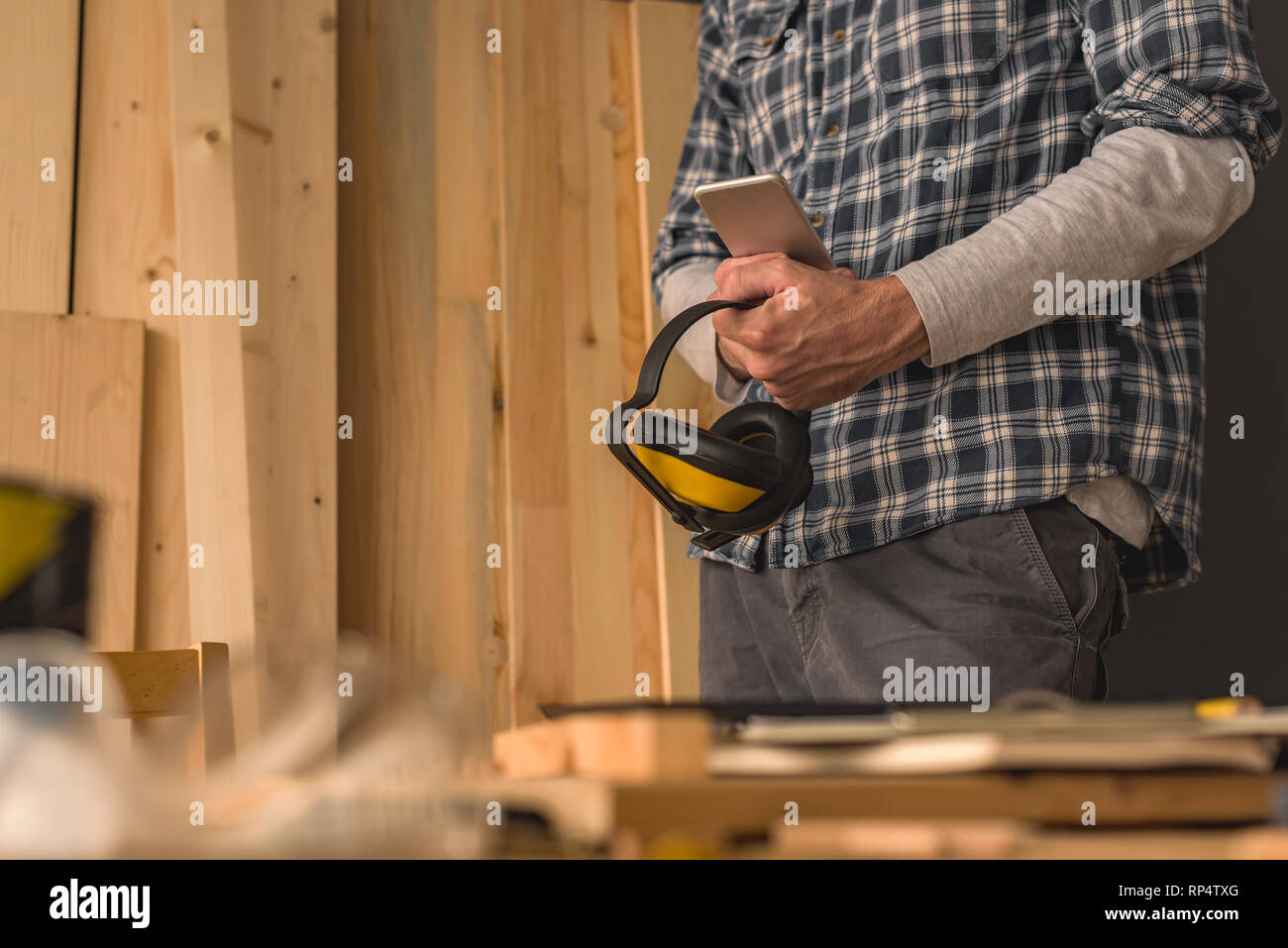 Carpenter using smartphone in small business woodwork workshop for planning a new DIY project Stock Photo