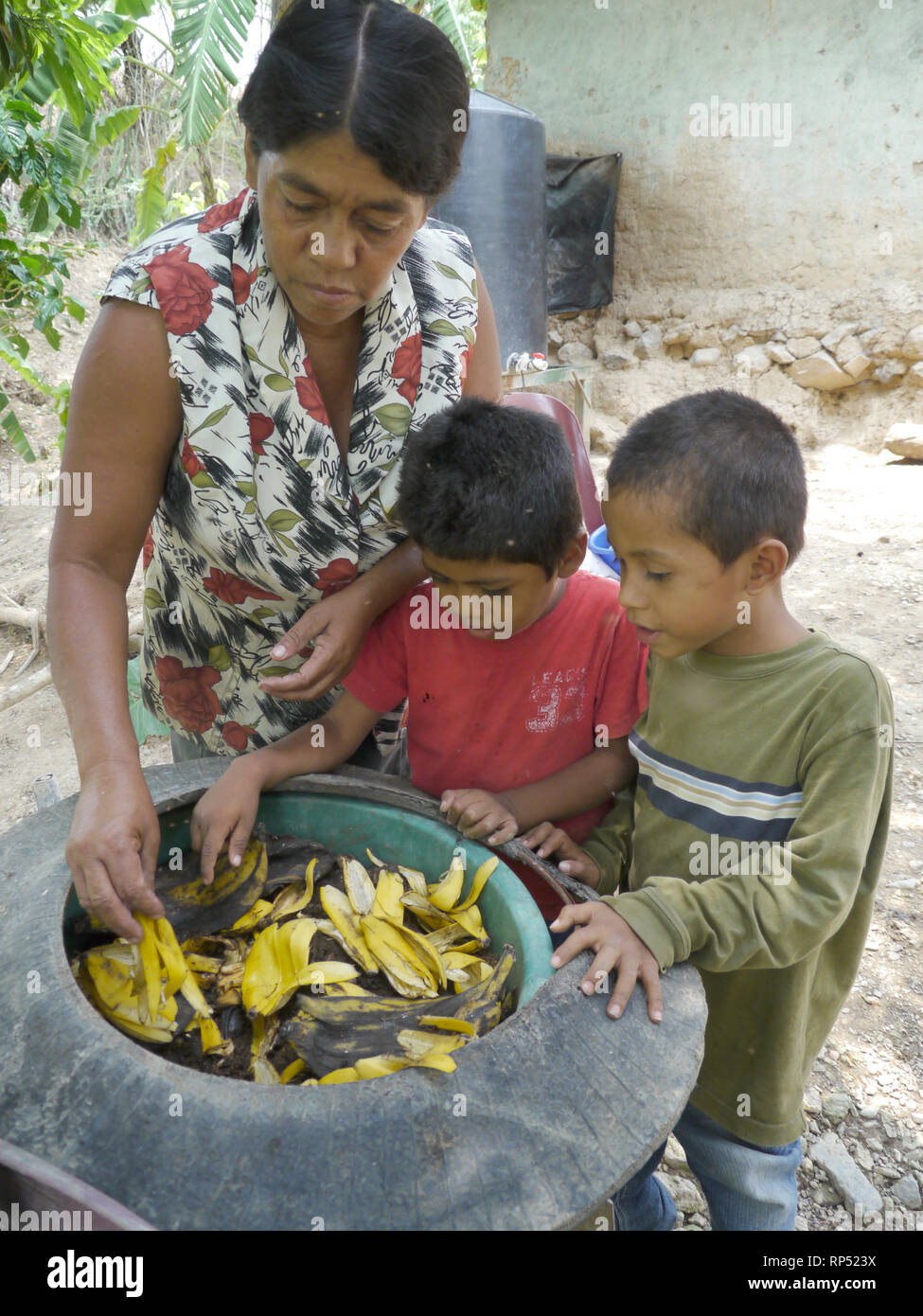 Nicaragua  FEDICAMP projects. Home of Reyna Margarita Vanegas (58) and her two sons Jose Armado Prado (4) and Junerling Prado (3). Worm culture for making compost. Reyna and the boys examine the pot in which the worms breed. Stock Photo
