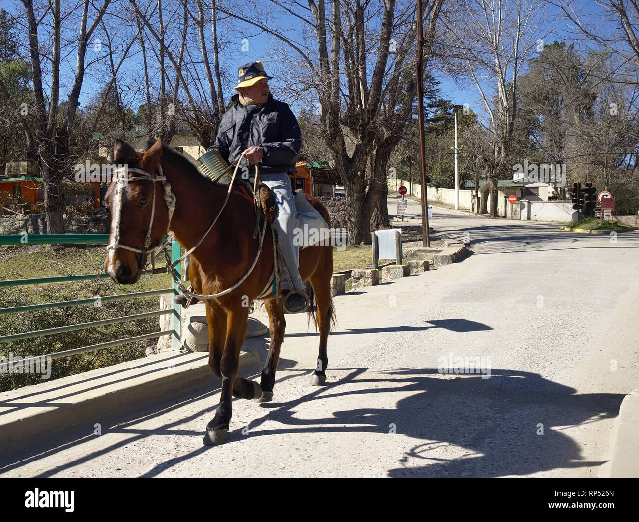 Cuesta Blanca, Cordoba, Argentina - 2018: A local man rides a horse across a bridge over the San Antonio river. Stock Photo