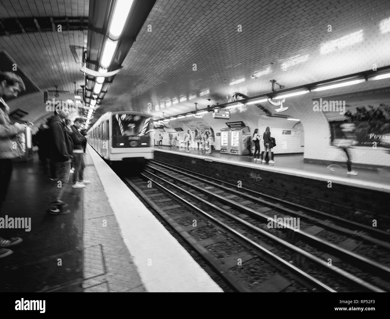 PARIS, FRANCE - OCT 13, 2018: Black and white image of commuters large crowd of people waiting in the Montparnasse bienvenue metro subway station for their train commuting in the metropolitain of paris perspective view Stock Photo