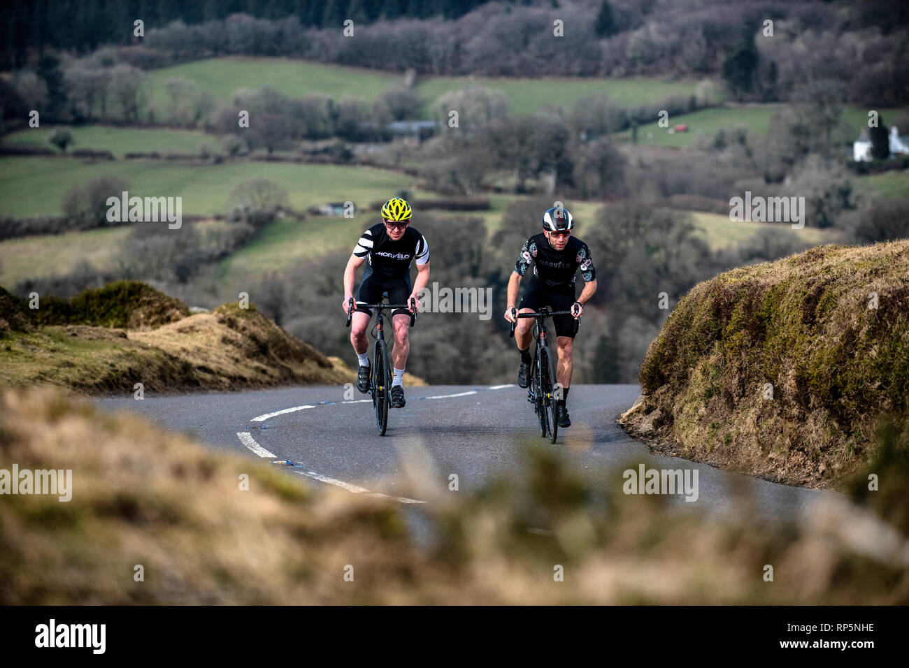 Two cyclist climb a hill on a road on Dartmoor in Devon. Stock Photo