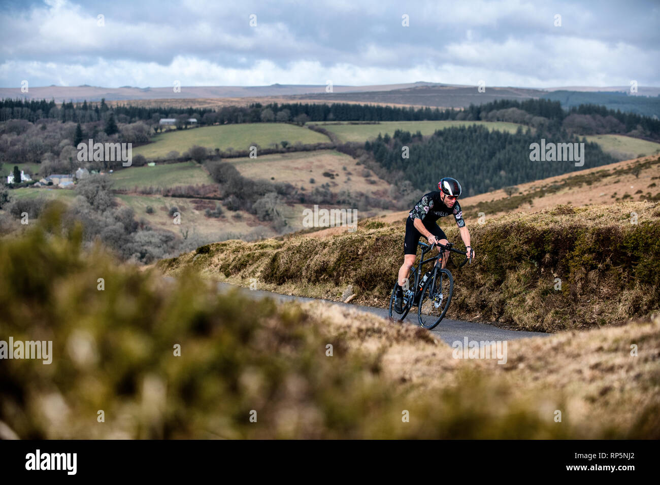 A cyclist climbs a hill on a road on Dartmoor in Devon Stock Photo Alamy