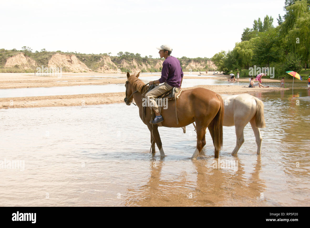 Nono, Cordoba, Argentina - 2019: A local man rides a horse at the Rio de los Sauces river. Stock Photo