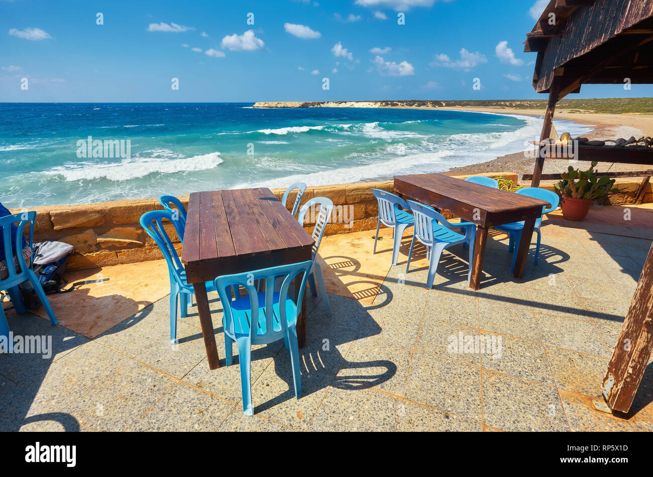 Tables and chairs in a cafe with palm trees on the beach Lara, Cyprus Stock Photo