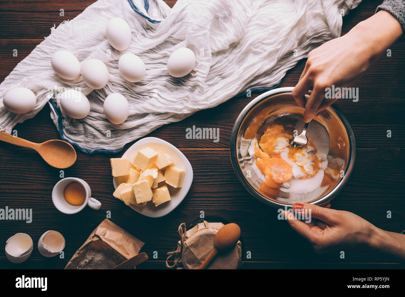 View from above woman's hands mixing sour cream, sugar and yolks in