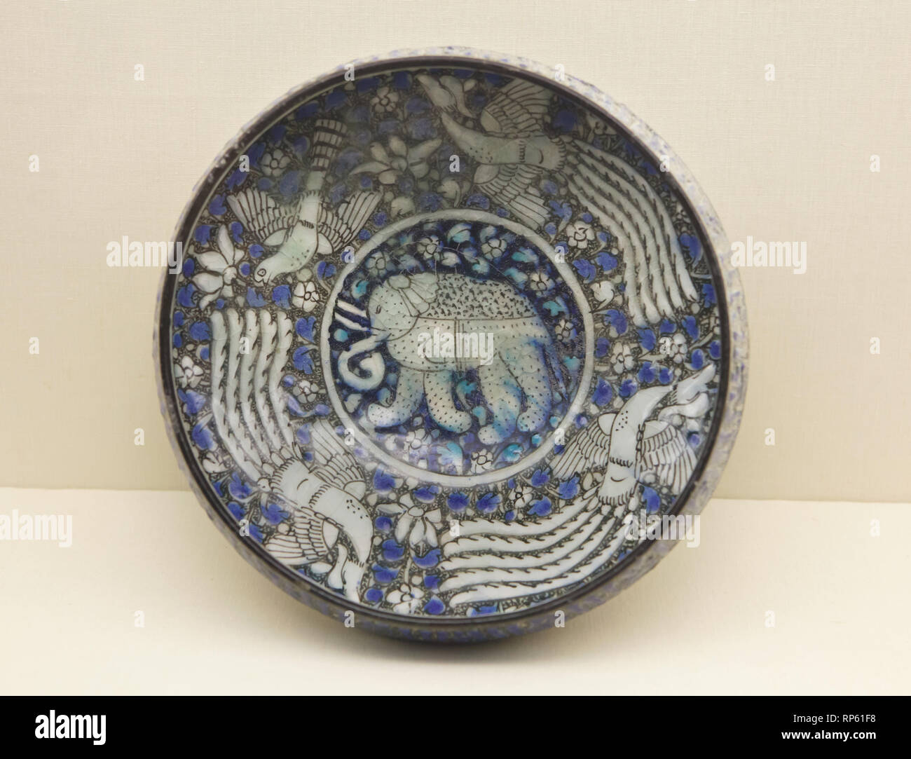 Iranian fritware (stone-paste) bowl with an elephant and three phoenixes painted under the glaze in Sultanabad style (probably from Kashan, Iran) dated from the 14th century on display in the Calouste Gulbenkian Museum (Museu Calouste Gulbenkian) in Lisbon, Portugal. Stock Photo