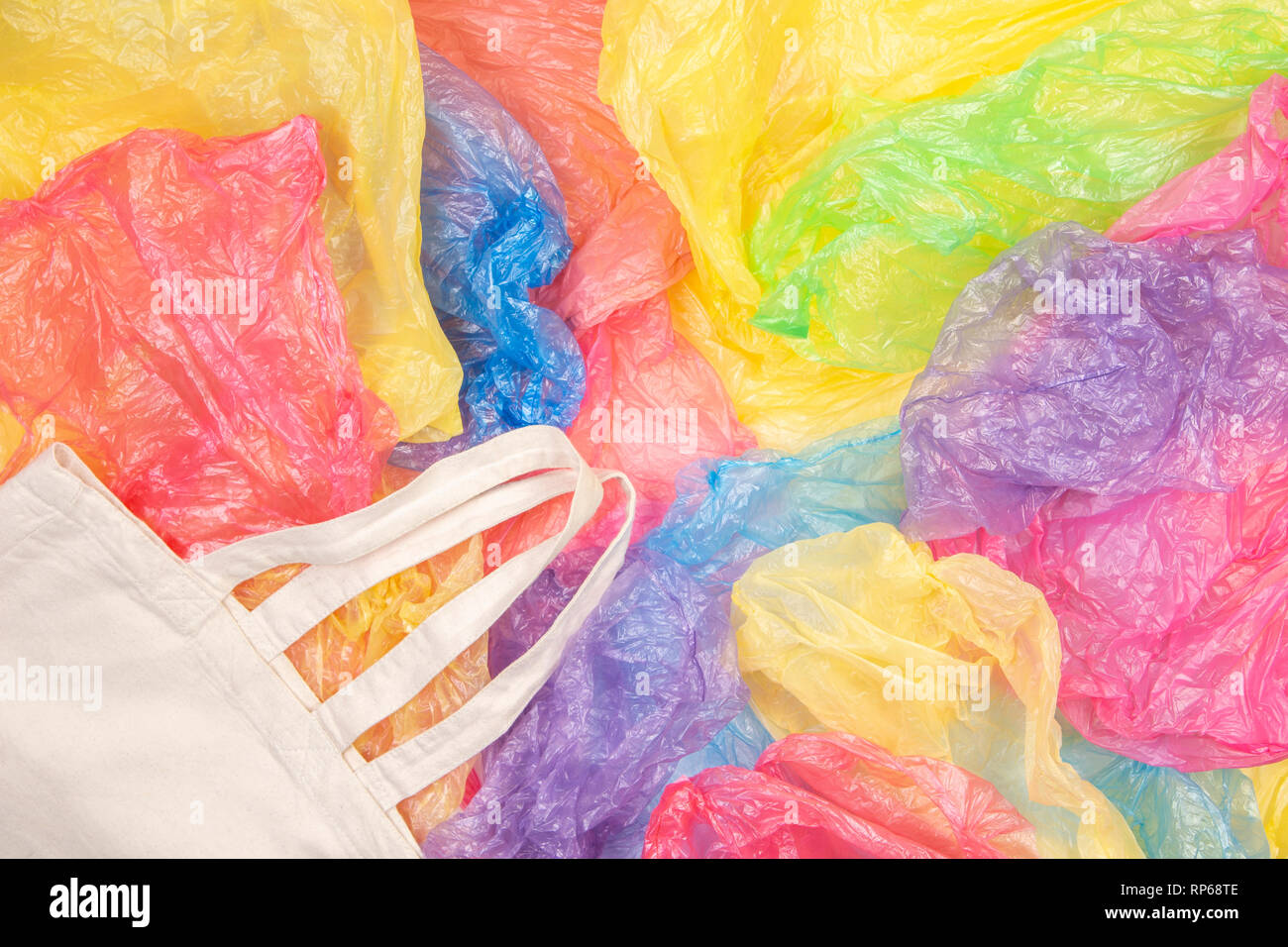 Many multicolored plastic bags with one eco natural reusable shopping bag background. Zero waste