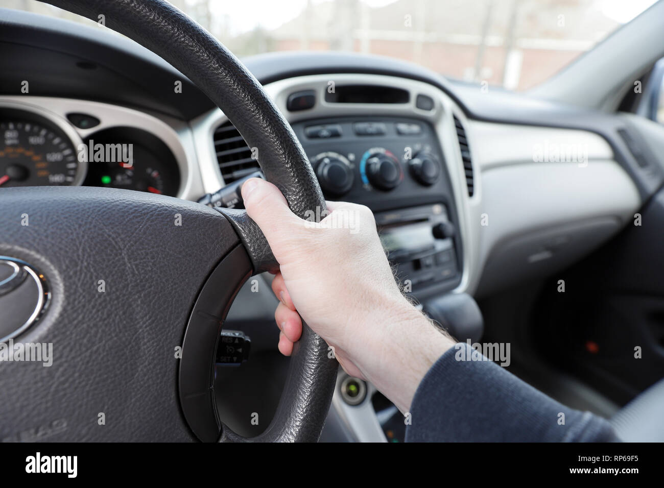 hand on vehicle steering wheel, gear shift, radio and climate controls