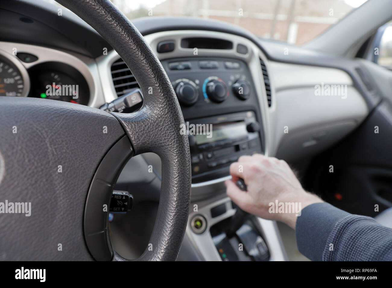hand on vehicle gear shift, gear shift, radio and climate controls