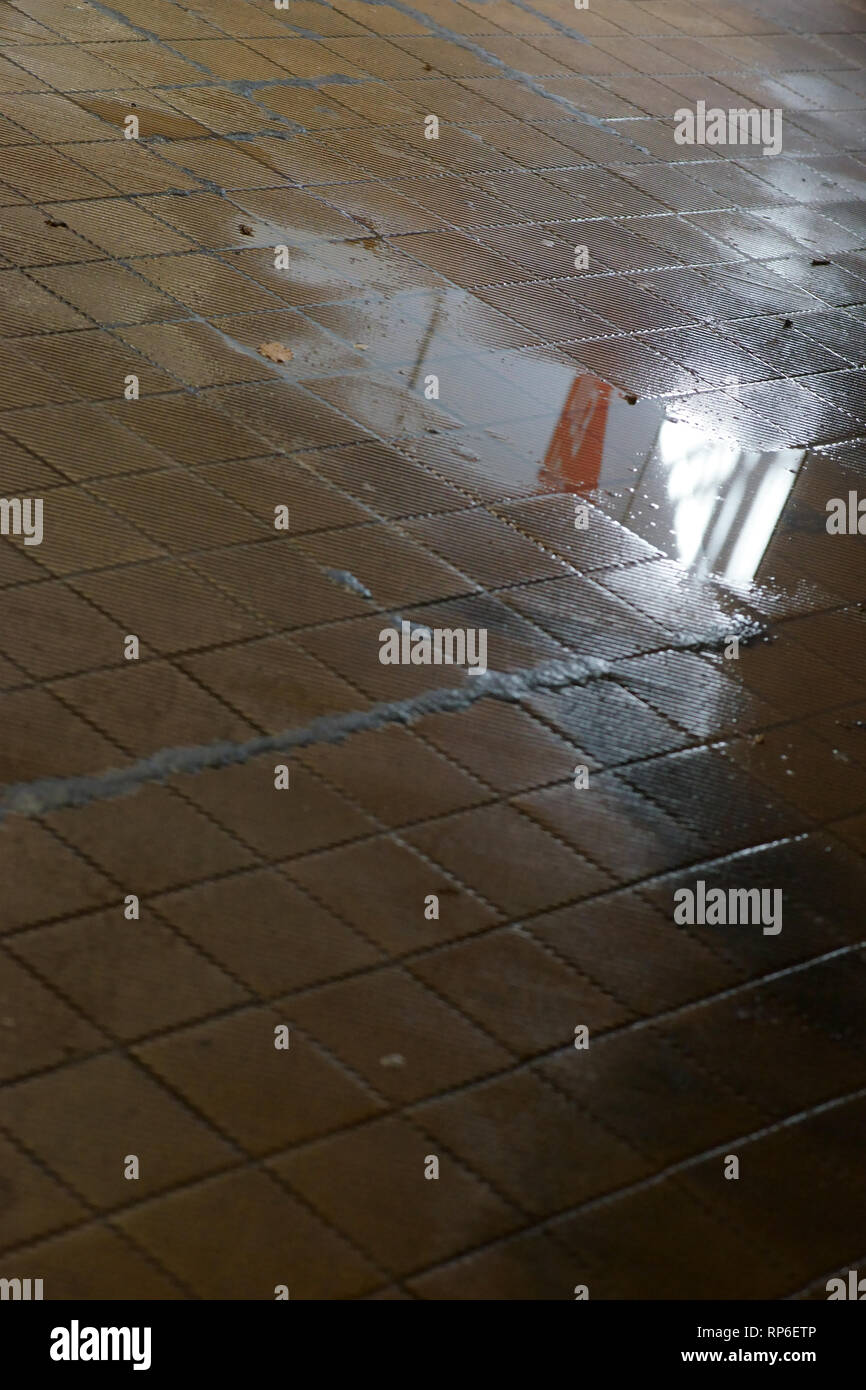 The old floor tiles of a station tunnel with puddles and damp walls. Stock Photo