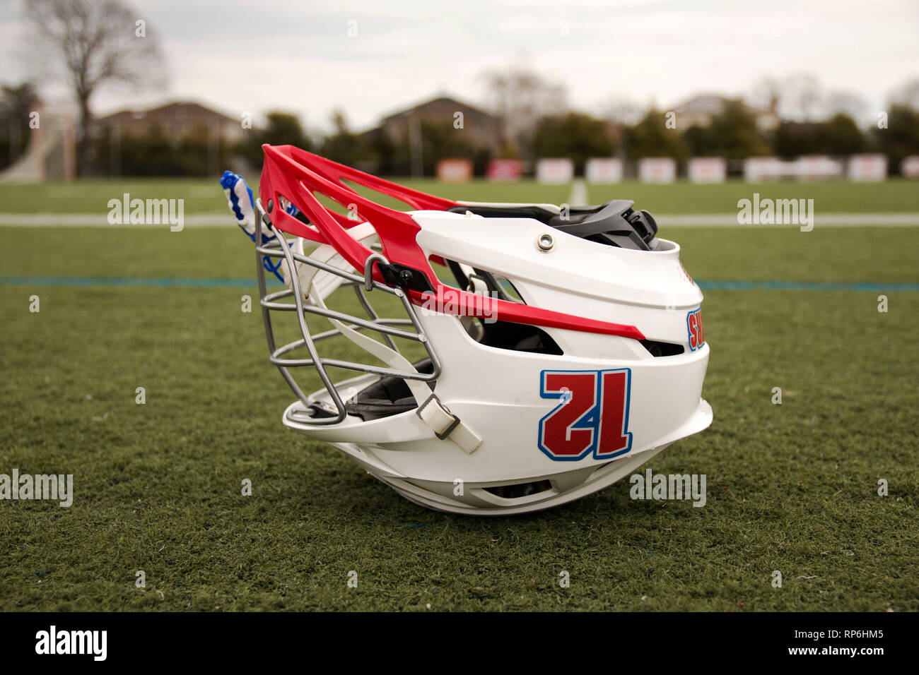 A lacrosse helmet is upside down on a green turf field Stock Photo