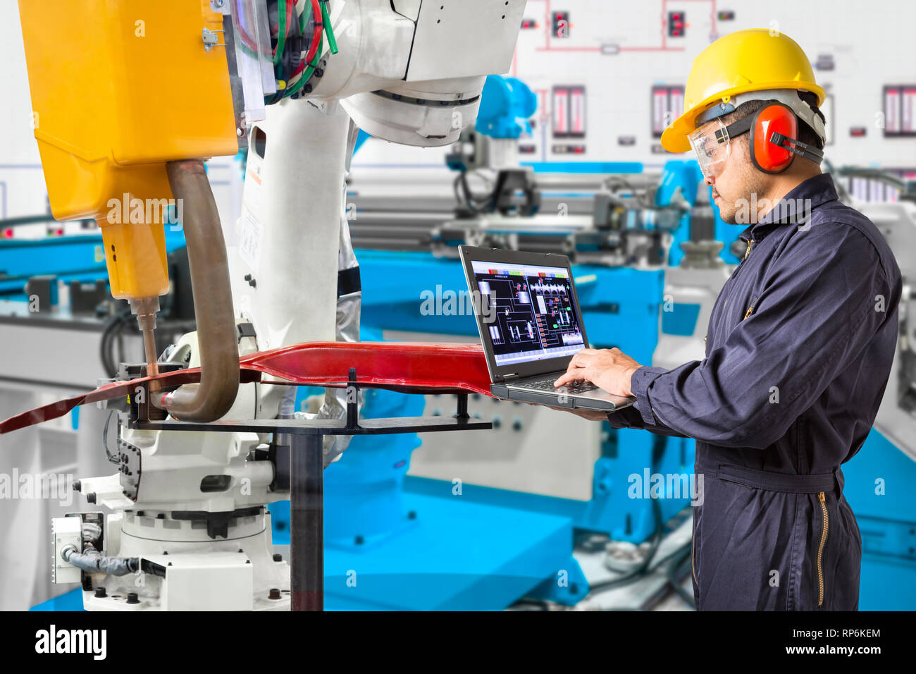 Engineer using laptop computer maintenance robot grip automotive workpiece position, Smart factory concept Stock Photo