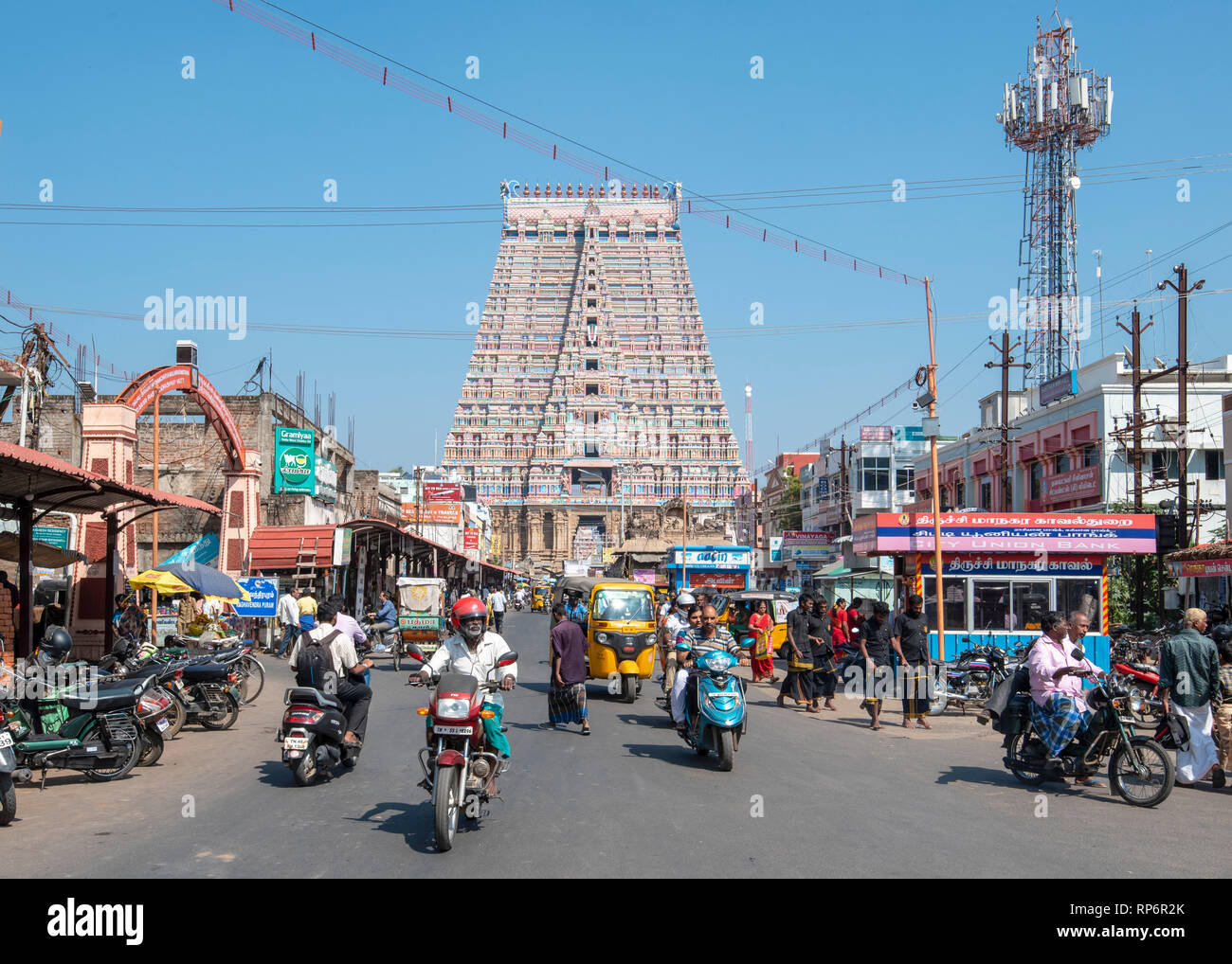 A busy street scene that leads to one of the main entrance to the Sri Ranganatha Swamy Temple in Srirangam on a sunny day with blue sky. Stock Photo