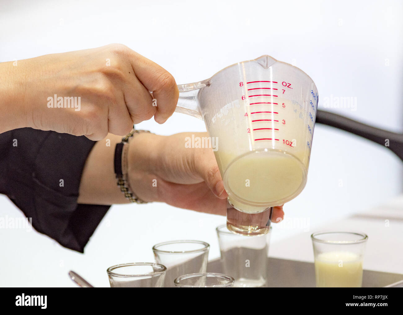 Measuring out milk in a measuring jug for cooking or test Stock Photo