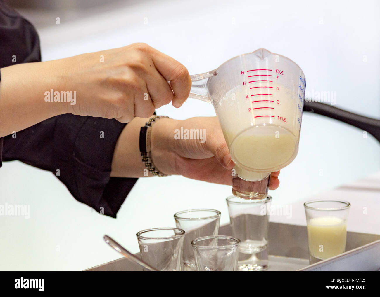 Measuring out milk in a measuring jug for cooking or test Stock Photo