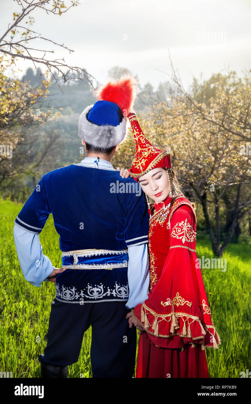 Couple in Kazakh costume in Spring Blooming apple garden at sunset of Almaty, Kazakhstan, Central Asia Stock Photo