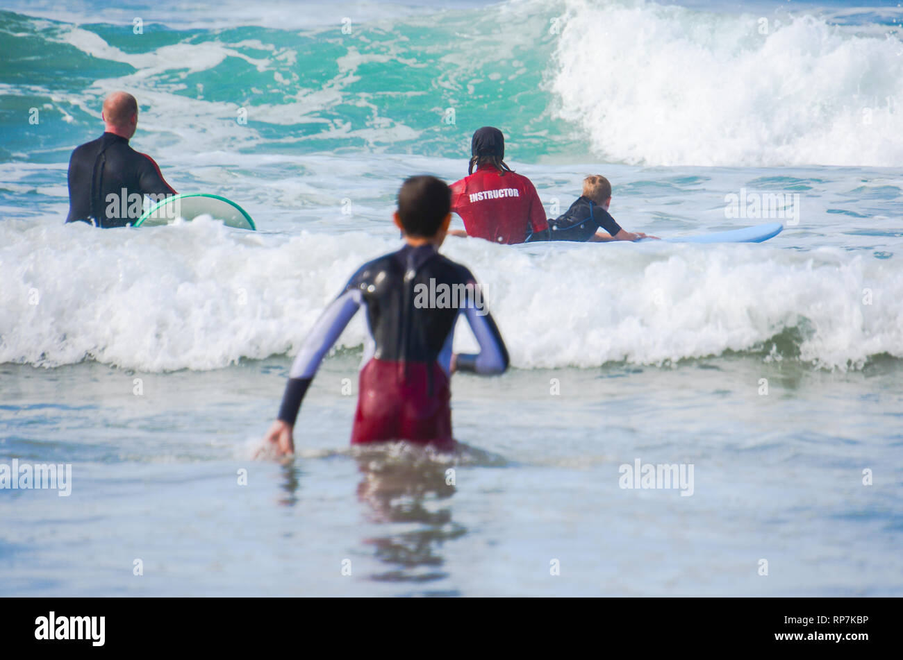 Beginner surfers learning to catch waves during surf lesson. Fun time during learn to surf lesson in the waves. Stock Photo