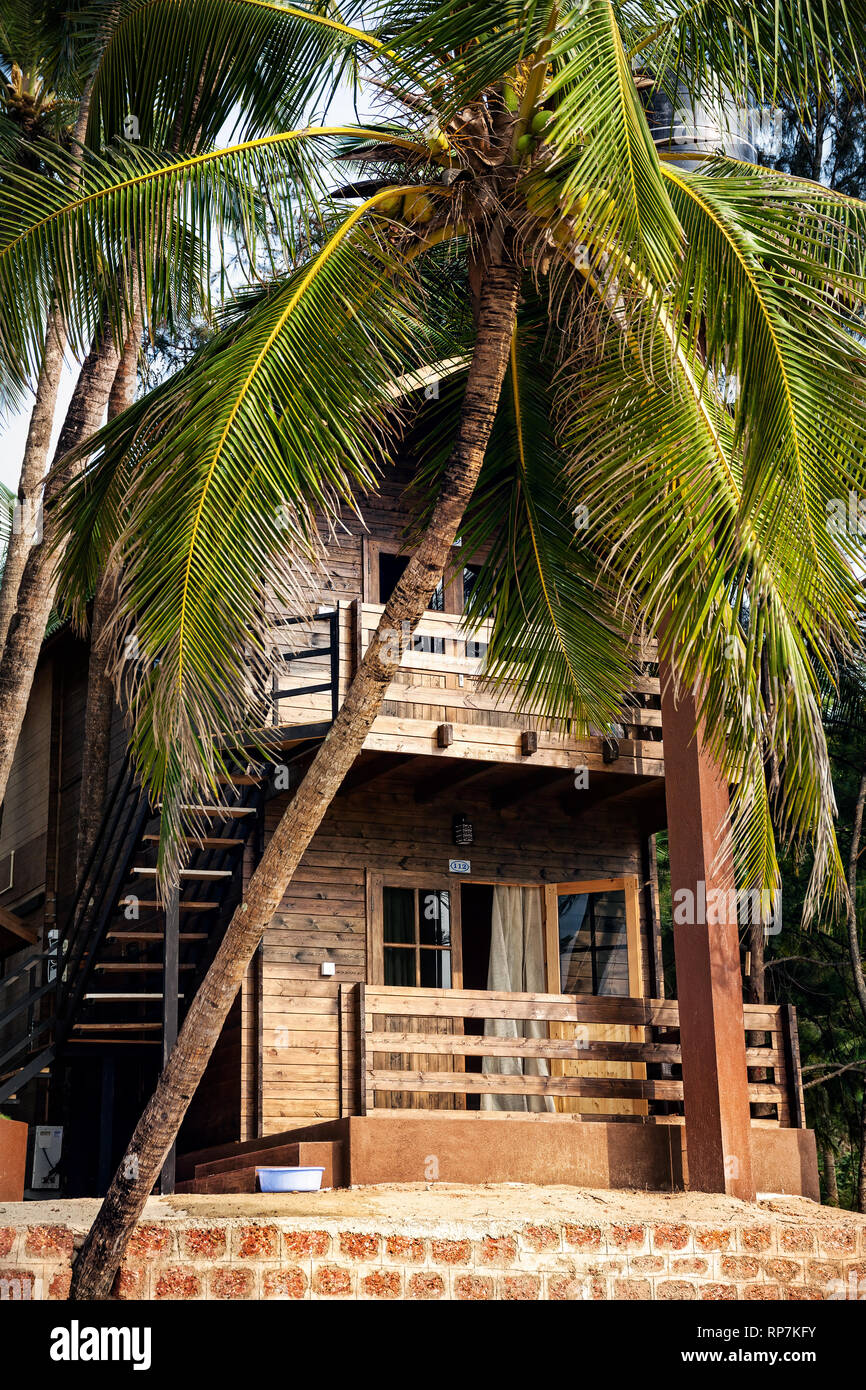 Tropical hotel on the beach with balcony and palm tree in Goa, India