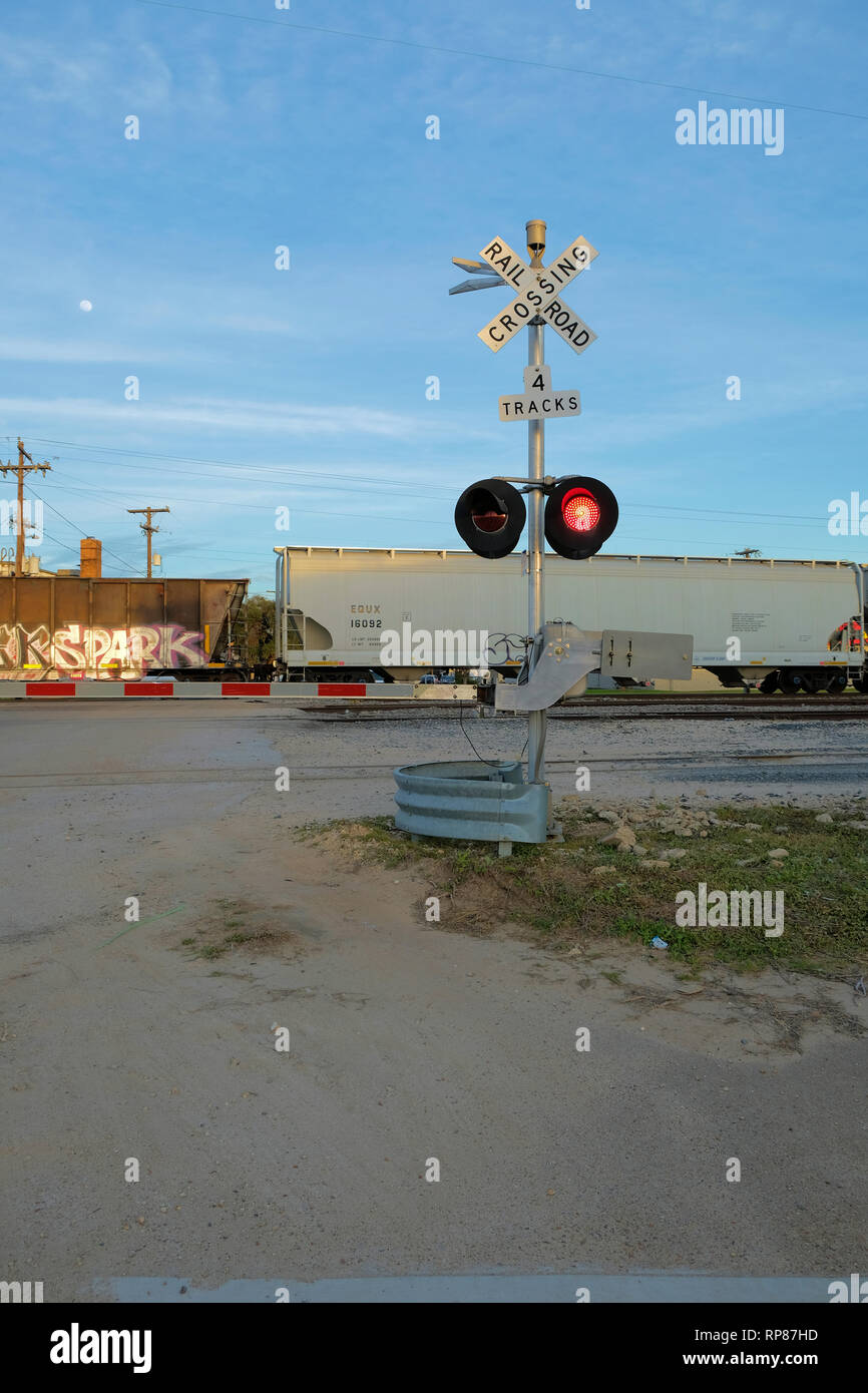 Railway boom barrier at a level railroad crossing with a train passing