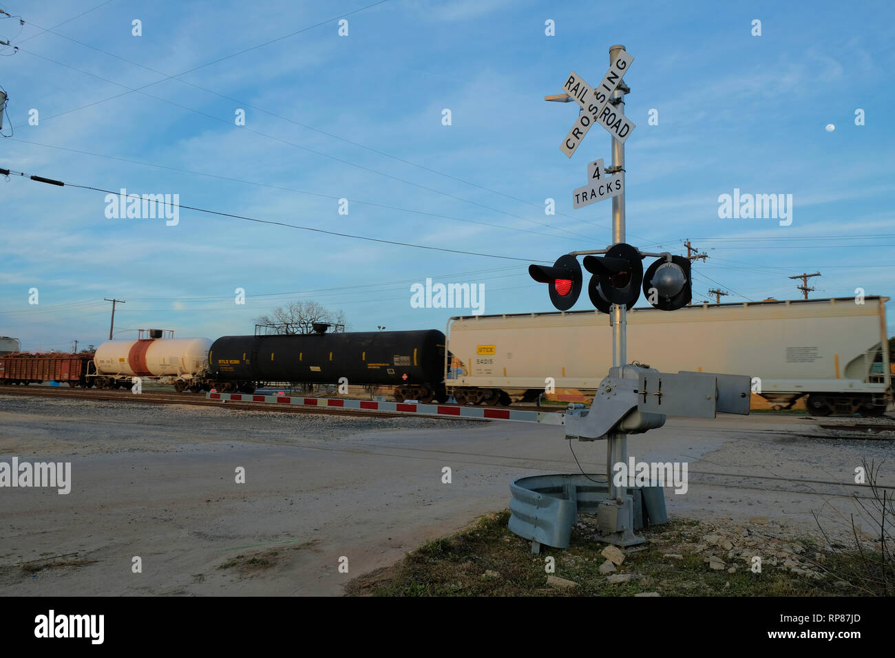 Railway boom barrier at a level railroad crossing with a train passing