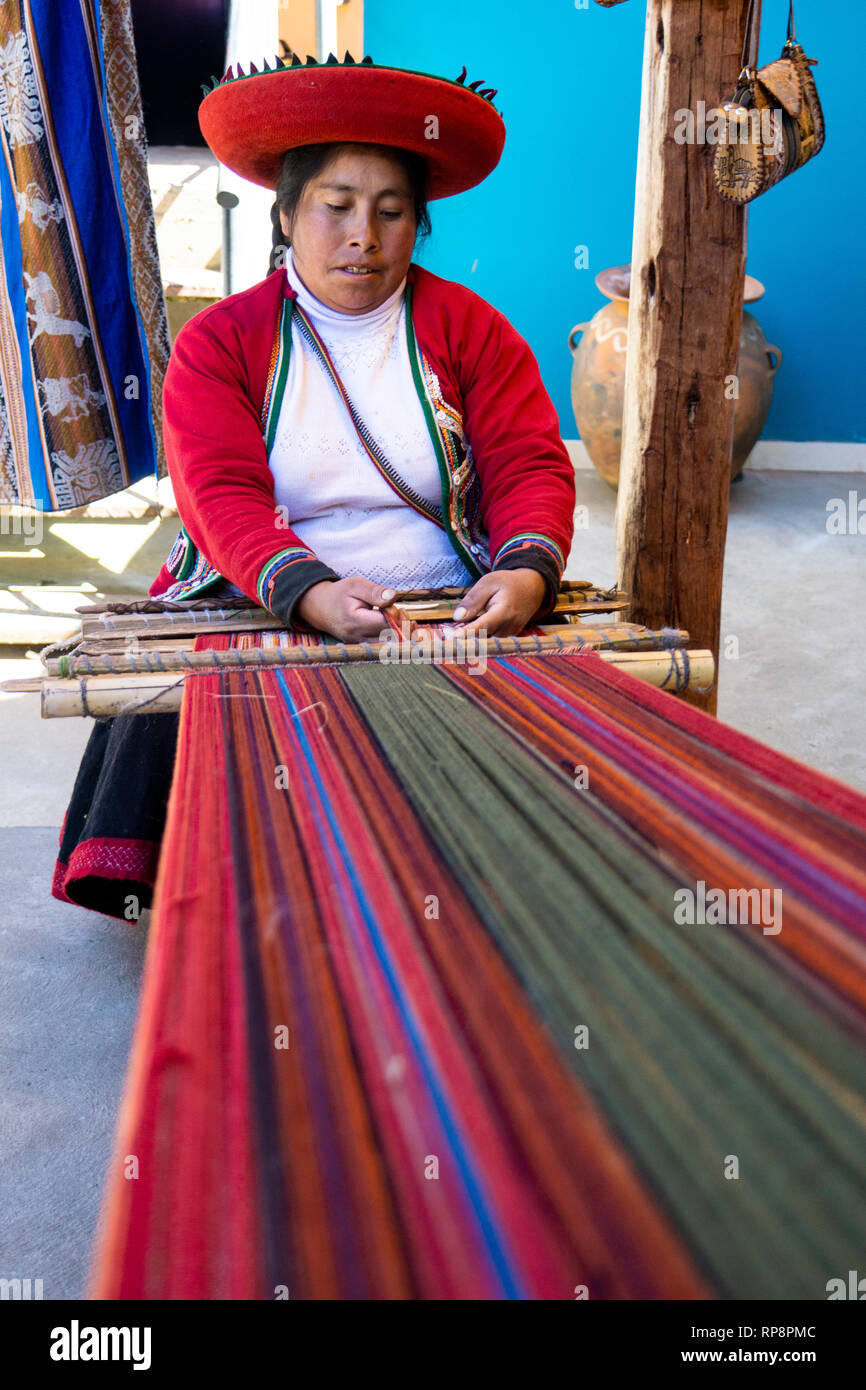 Woman in traditional dress weaves alpaca yarn in Sacred Valley, Cusco Region, Peru. Stock Photo