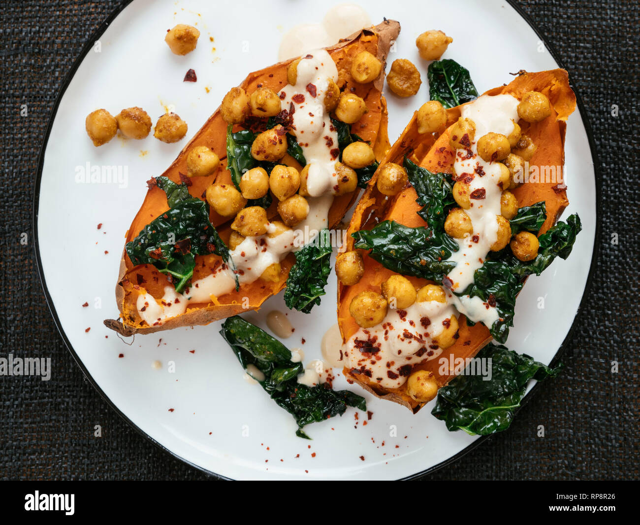 Baked sweet potatoes loaded with spicy chickpeas and kale and a tahini
