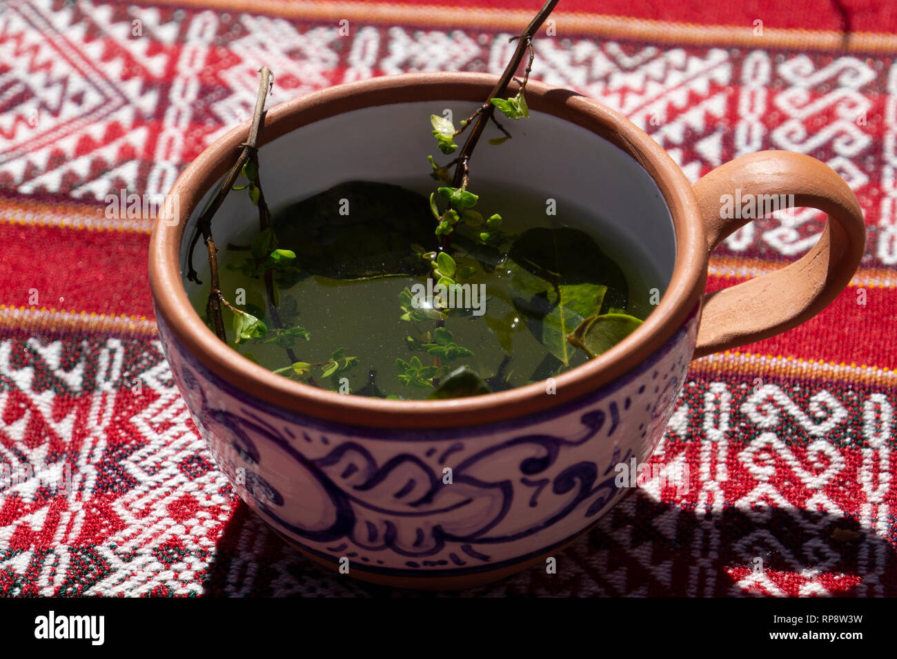 Traditional Incan herbal tea in handmade terra cotta clay mug on woven ...