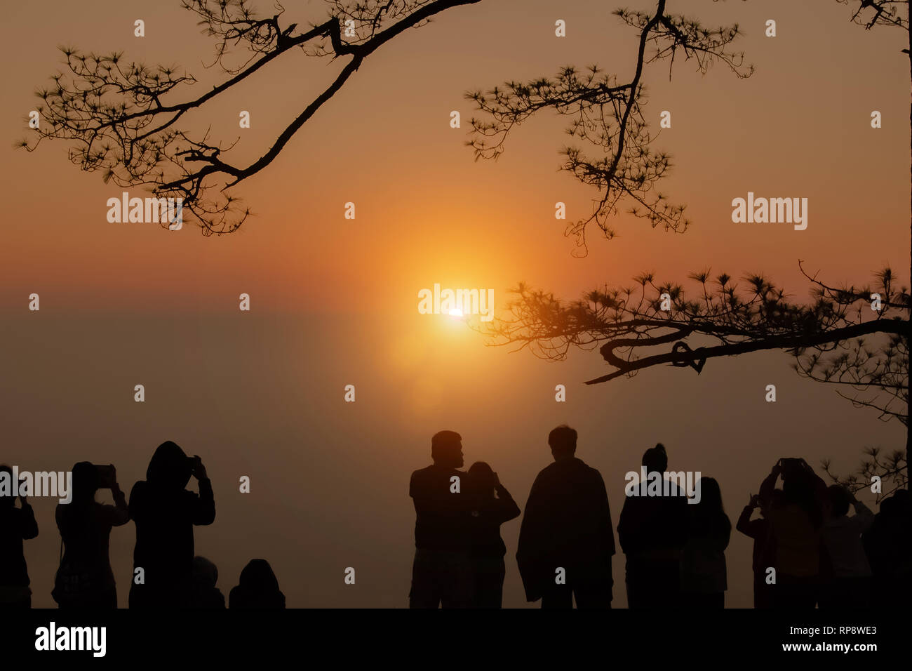 Vintage style of abstract blur field on orange bokeh light autumn sky at tree and young male photographer looking at scenery during golden hour sun ri Stock Photo