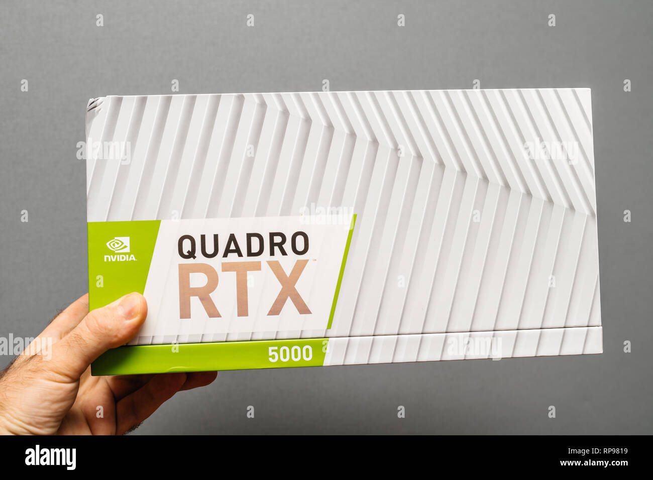 Paris, France - Feb 20, 2019: Man holding cardboard of latest Nvidia Quadro RTX 5000 workstation professional video card GPU for professional CAD CGI scientific machine learning front view Stock Photo