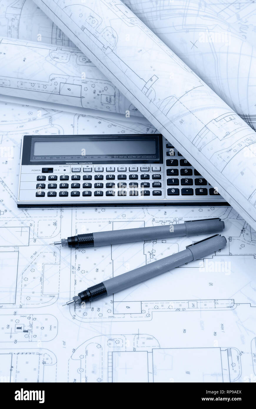 Architectural plans, calculator and drawing utensils. Picture in blue tone. Stock Photo