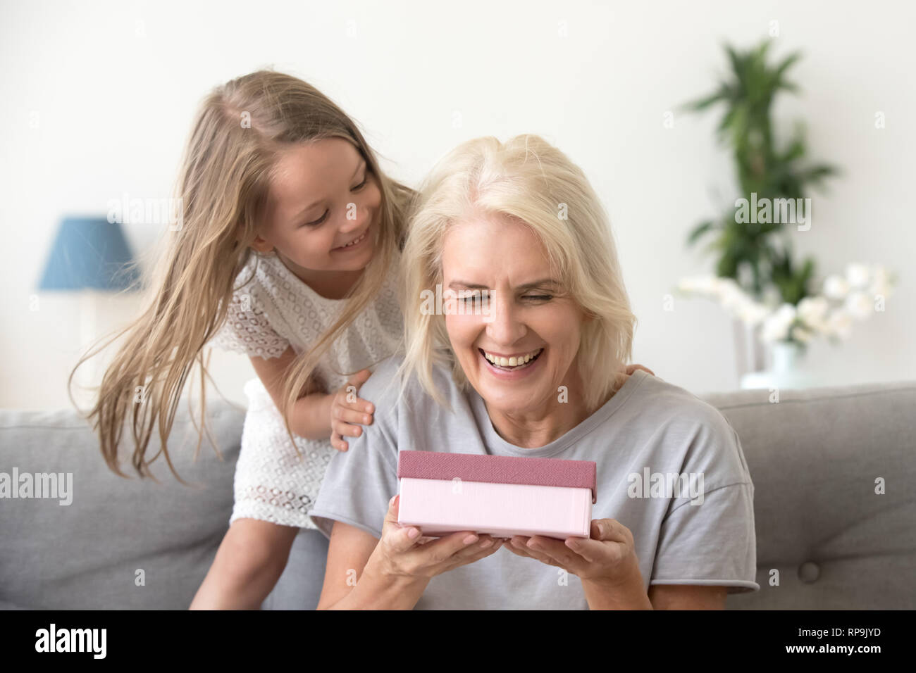 Happy grandmother receive box with gift from granddaughter Stock Photo