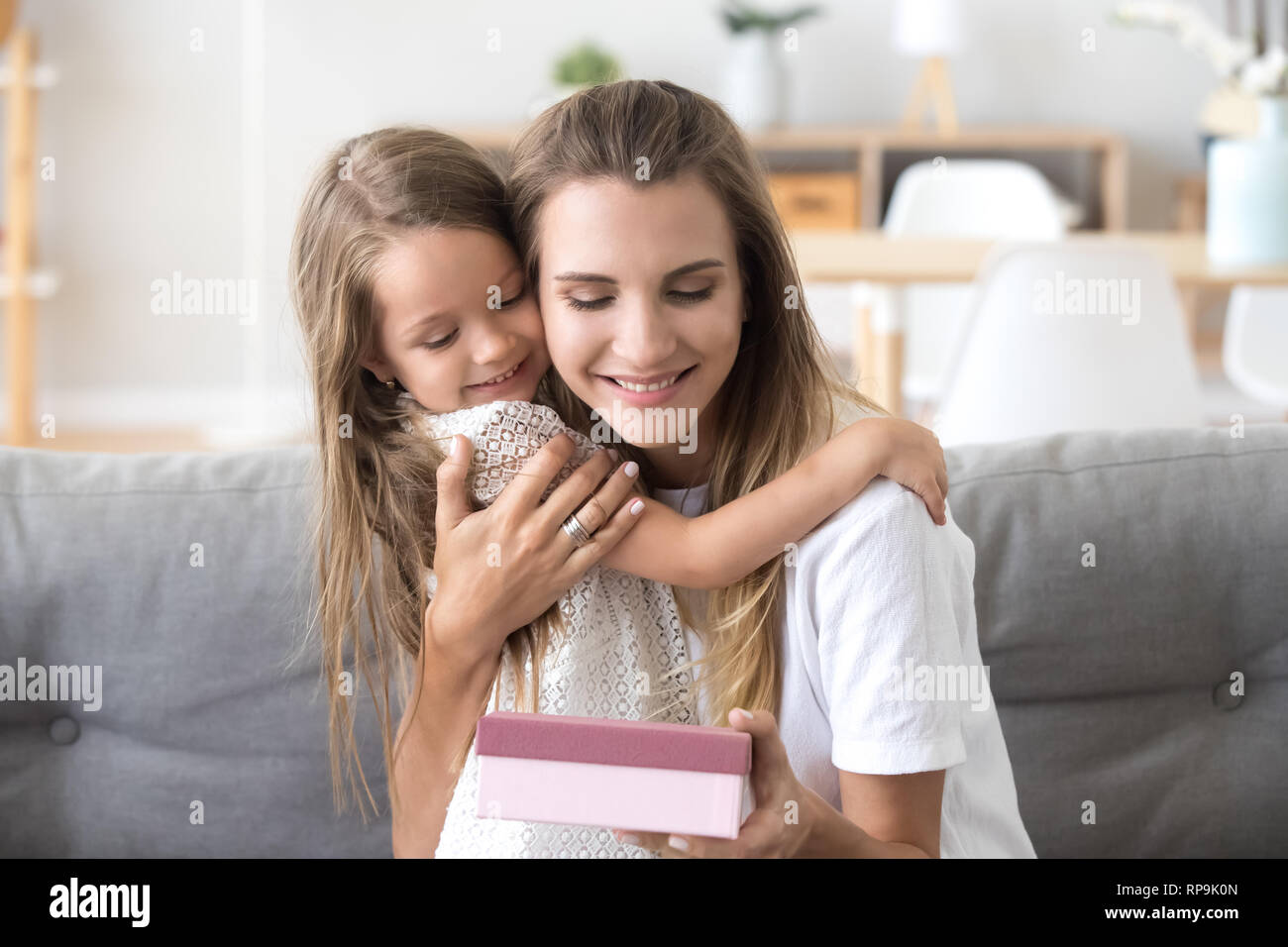 Loving happy mother embracing, thanking little daughter for present Stock Photo