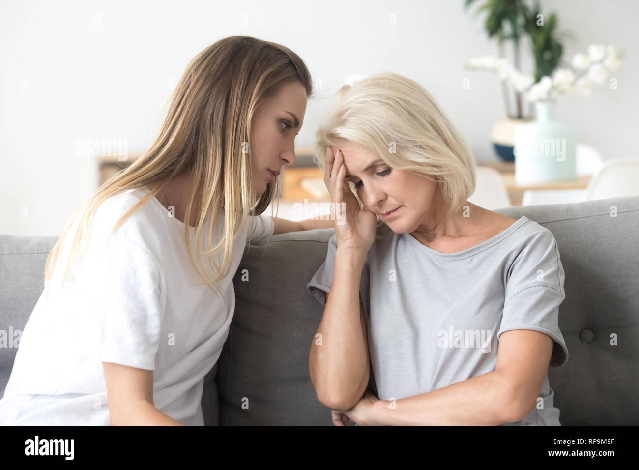Loving daughter comforting, consoling aged upset mother at home Stock Photo