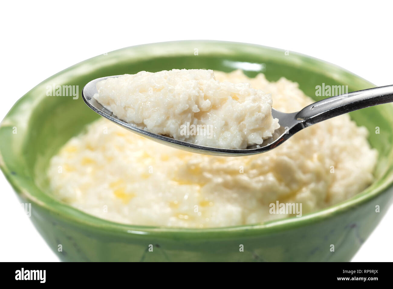 Rice porridge for breakfast with butter in a green bowl and spoon. Stock Photo