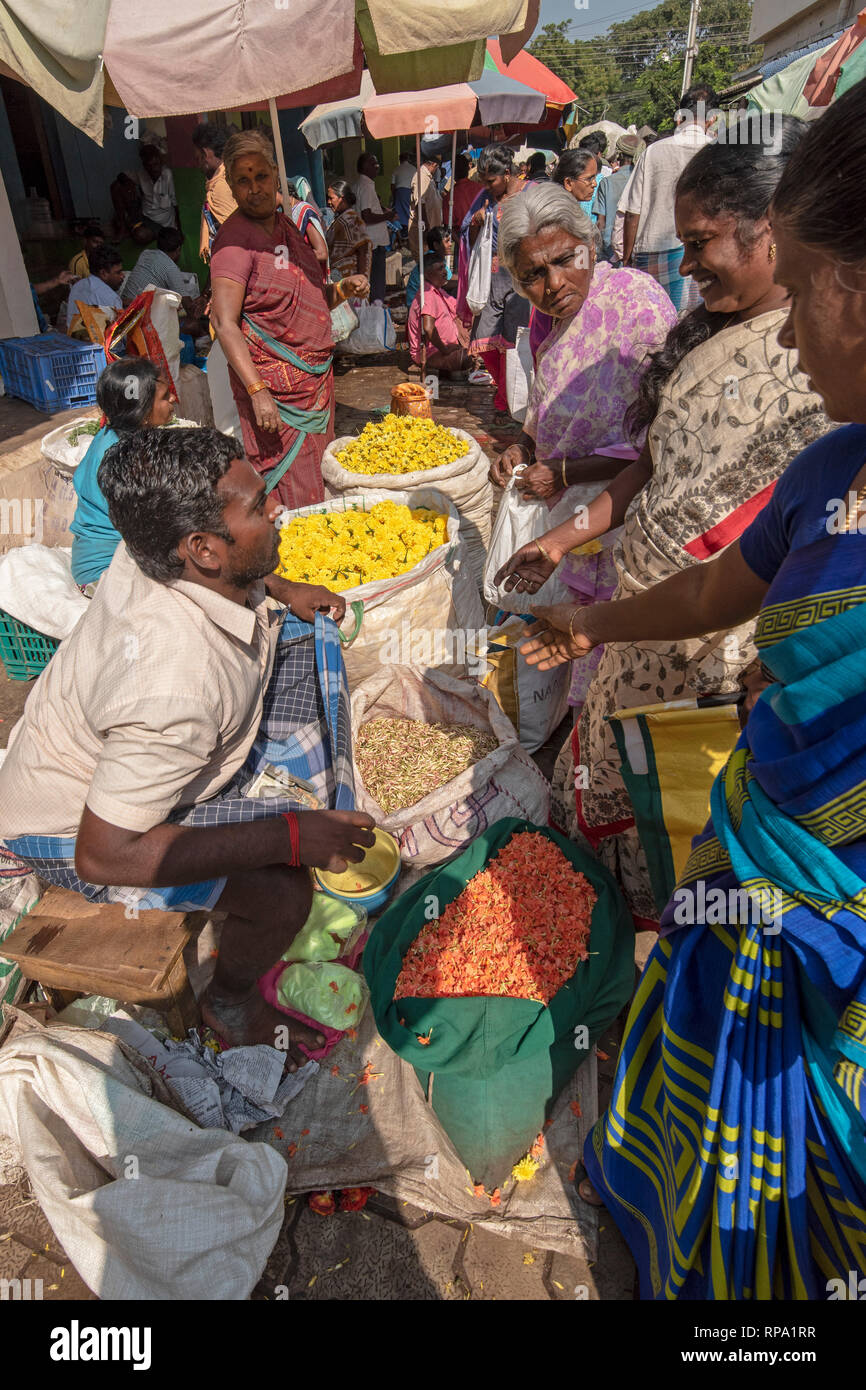 A buyer of flowers handing over the money to the seller for a transaction at the busy bustling Madurai flower market. Stock Photo