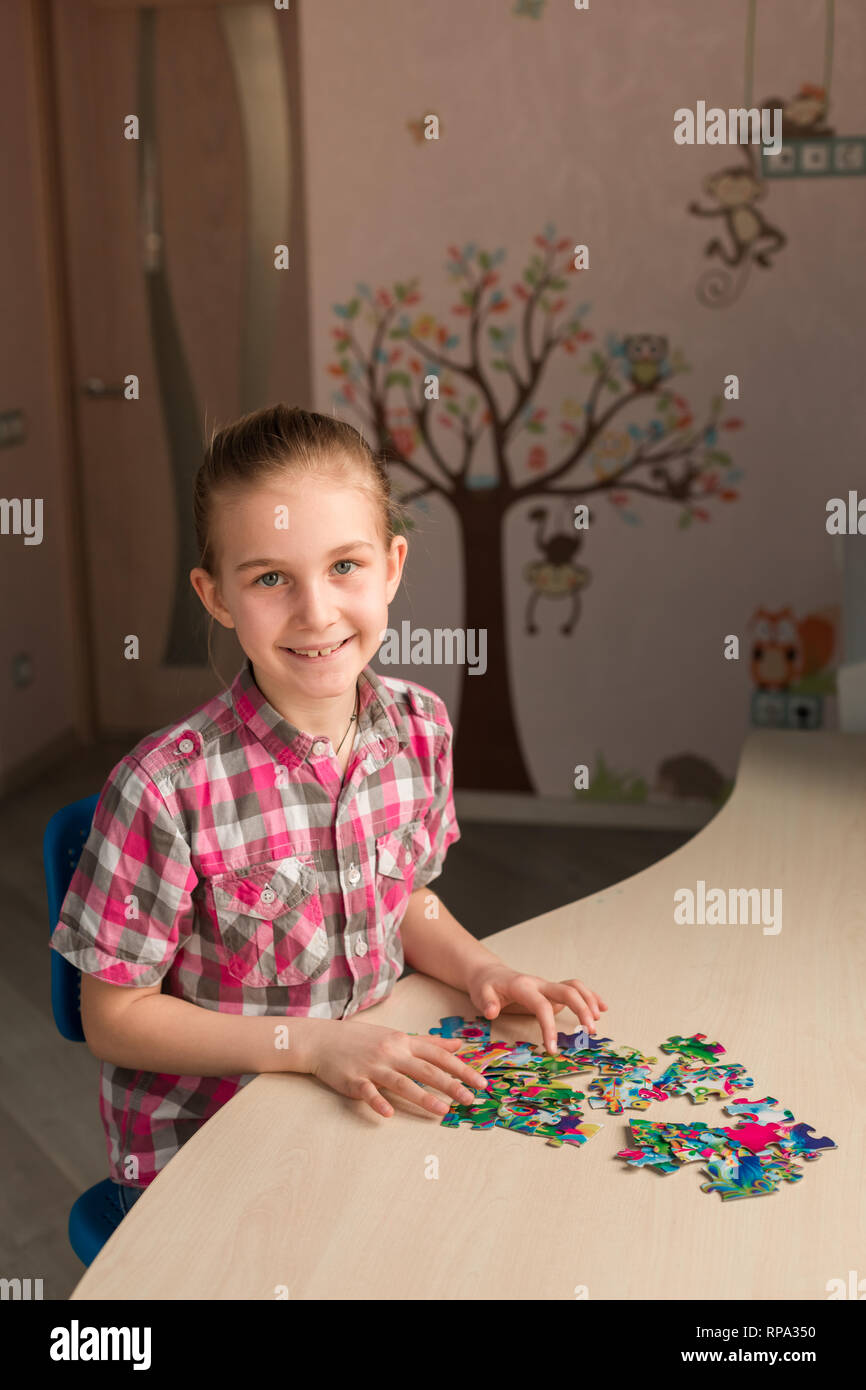 Cute little girl solving puzzle together sitting at the table Stock Photo